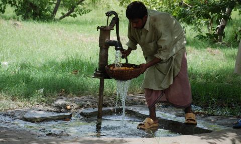 Photo of a man pumping water at a water pump