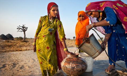 Women fill water vessels from a concrete Taankas, underground rainwater harvesting tanks