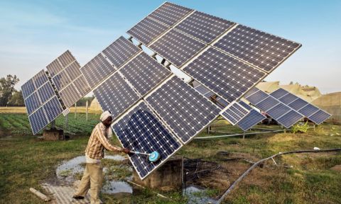 A farm worker in India cleans solar panels