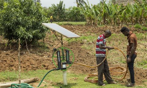 Two farmers set up pump with solar panel