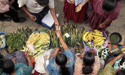 Overhead shot, women at bottom selling vegetables to customers at top