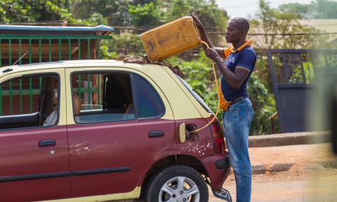 Man holding gas tank against roof of car