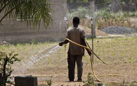 A farmer in Ghana uses a sprinkler irrigation system