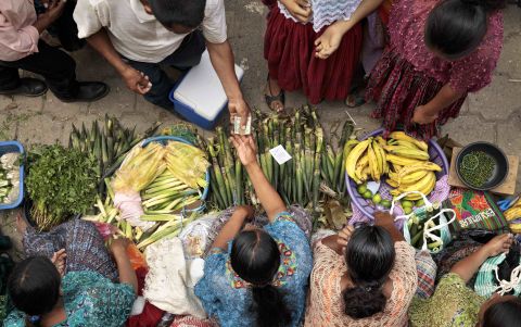 Overhead shot, women at bottom selling vegetables to customers at top