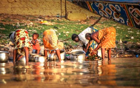 Women wash pots in a river in Mali