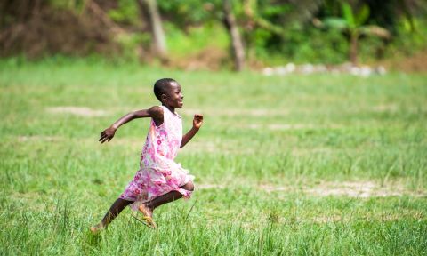 Girl runs through a field.
