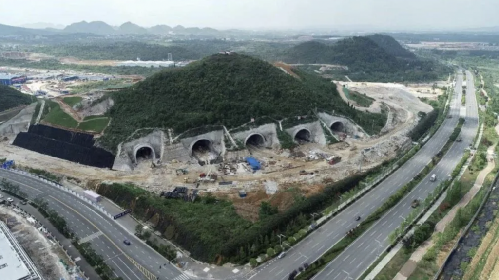 Large hill with with tunnel entrances, between two highways