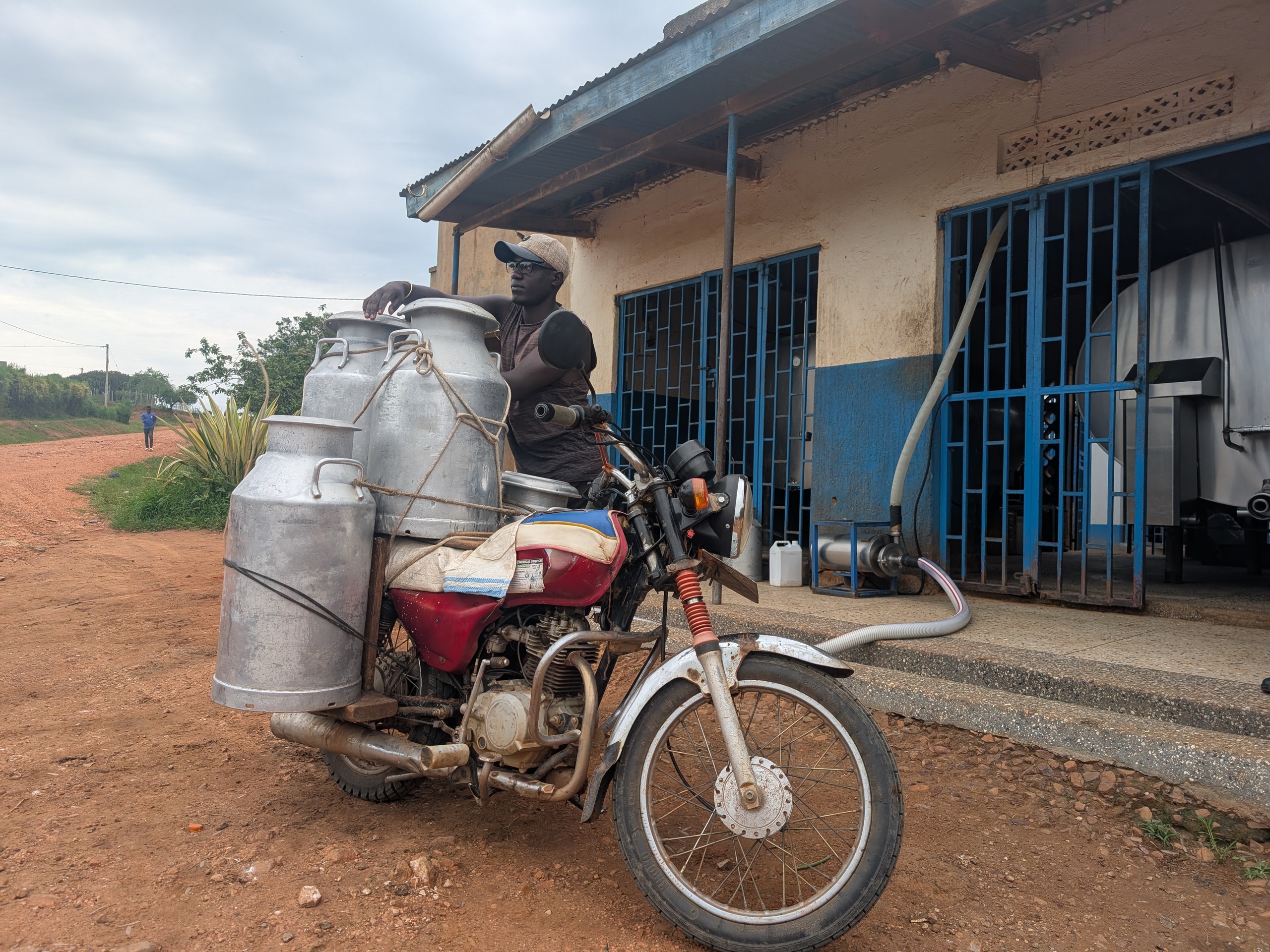 A man riding his motorbike loaded with milk canisters.