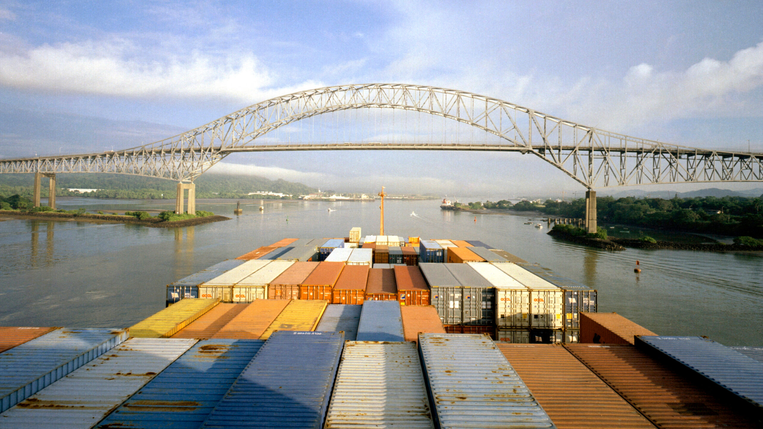 Overhead view of containers on front of ship, foreground, facing bridge in distance.