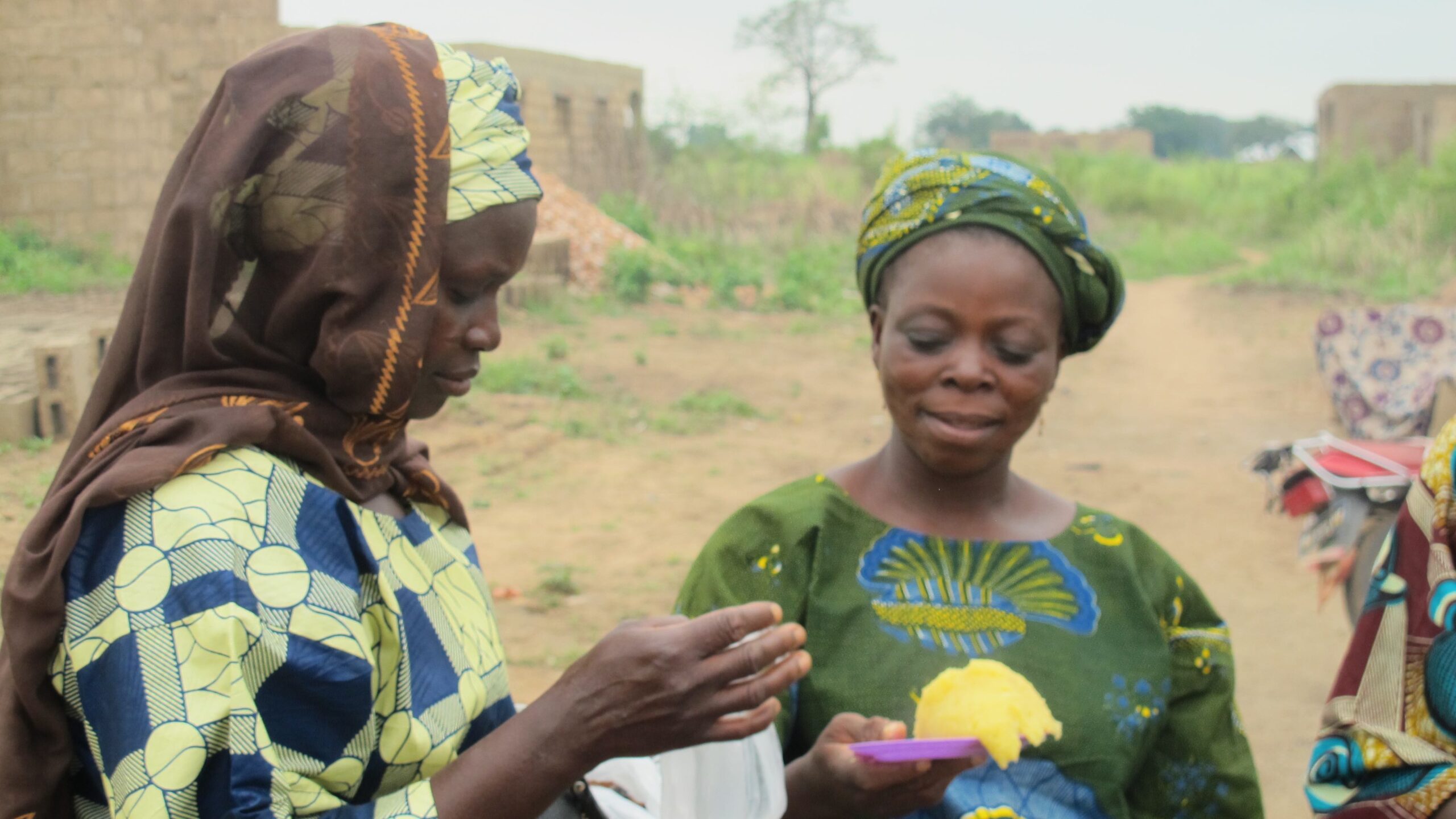 Two women, one on right holding plate with cassava