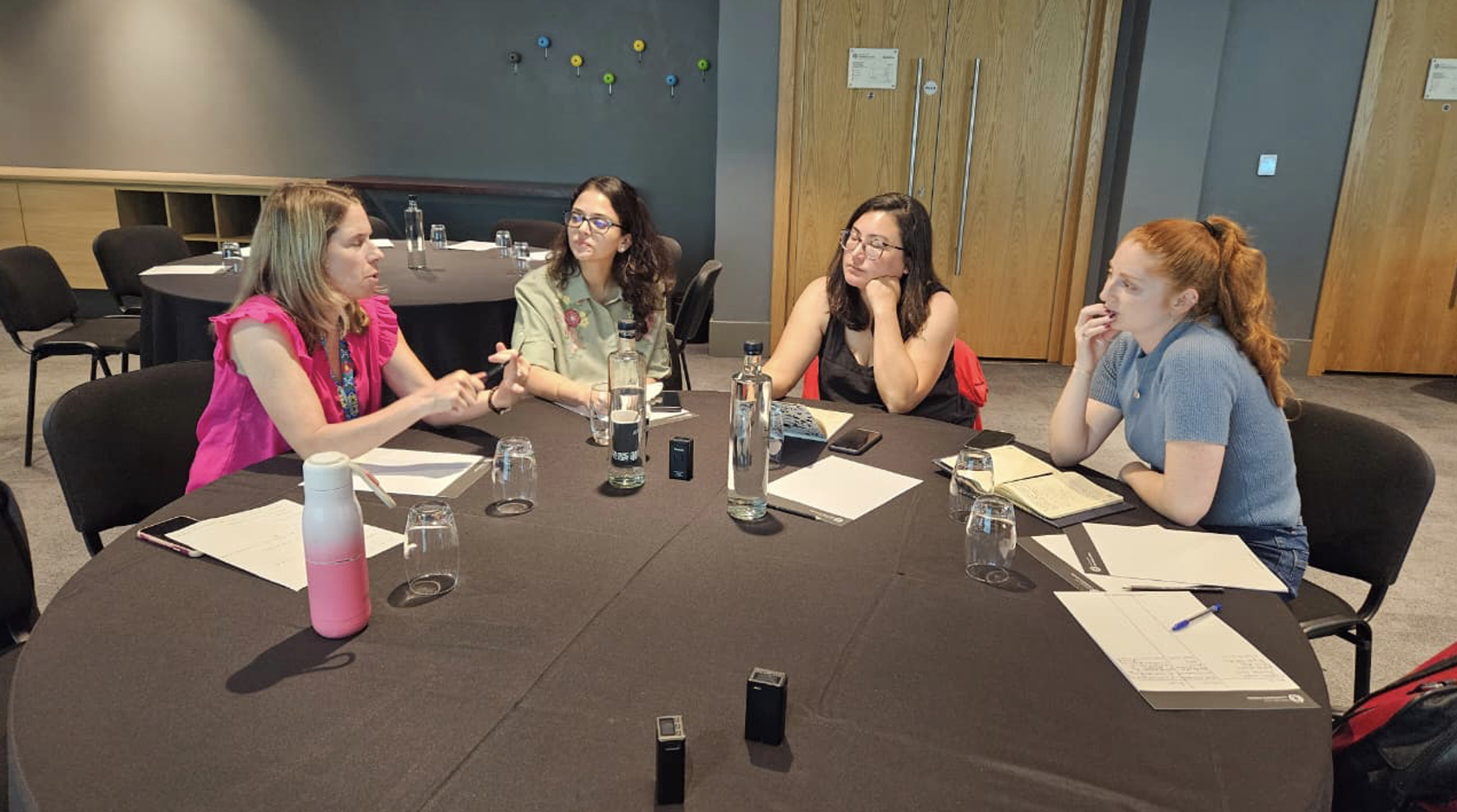 Four women sitting around table in discussion.