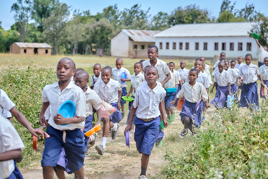 School children in uniforms running and holding bowls